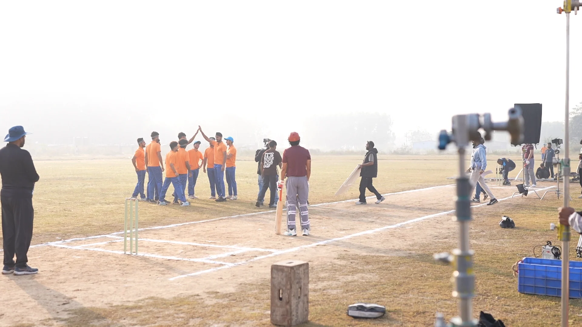 Cast and camera crew filming on a sports field
